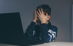 Bambino davanti al PC si copre il volto